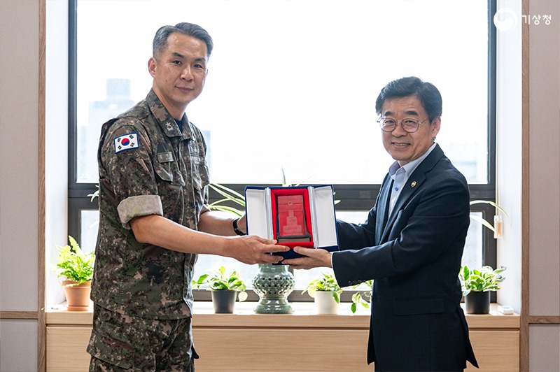 장동언 기상청장이 해군 관계자에 측우기가 묘사된 기념품을 전달하는 모습