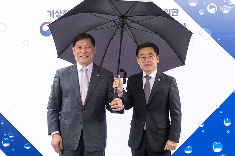 허구연 한국야구위원회 총재와 장동언 기상청장이 우산을 함께 쓰고 기념촬영하는 모습